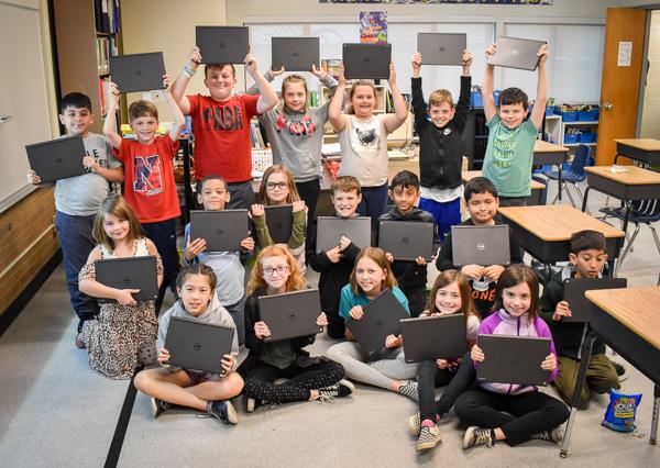 Students at Hoover hold up their Chromebooks