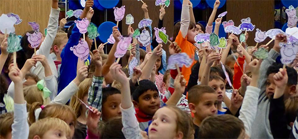 Students hold signs at author assembly