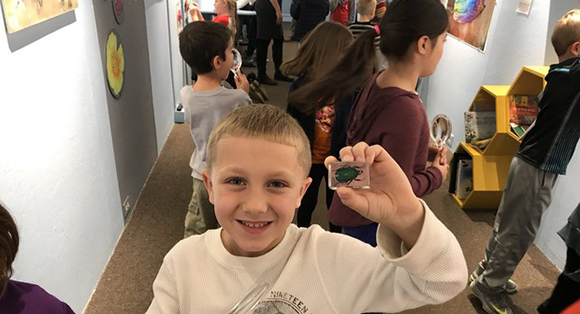 Student holds up spider art in the Artmobile