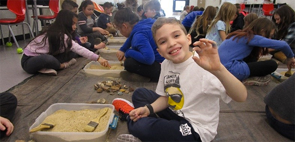 Tawanka student holds up a rock next to trays of dirt