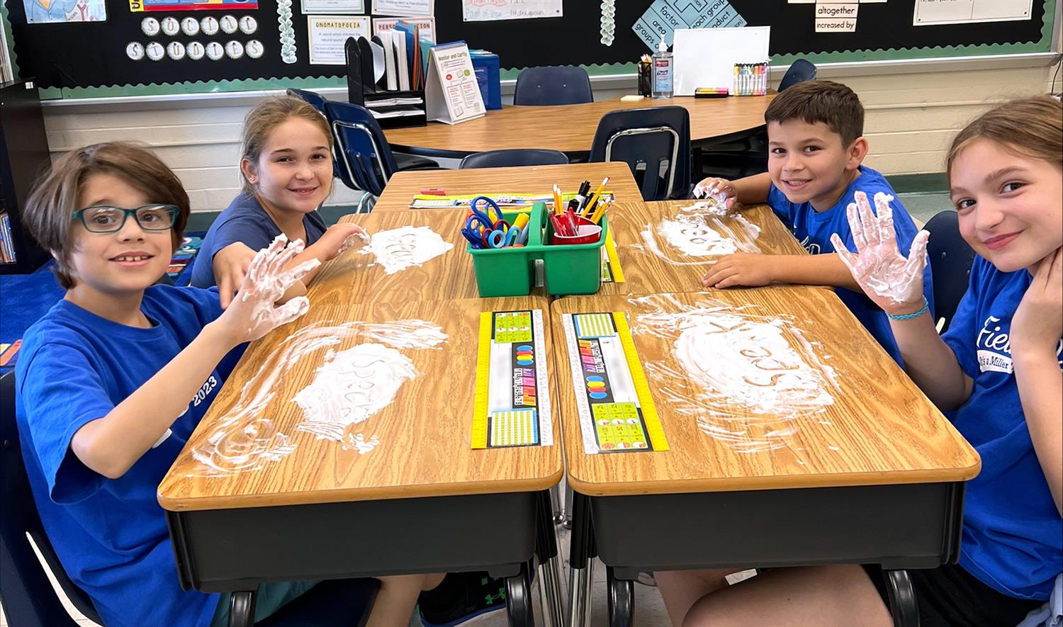 Students practice spelling by making words in shaving cream on their desks